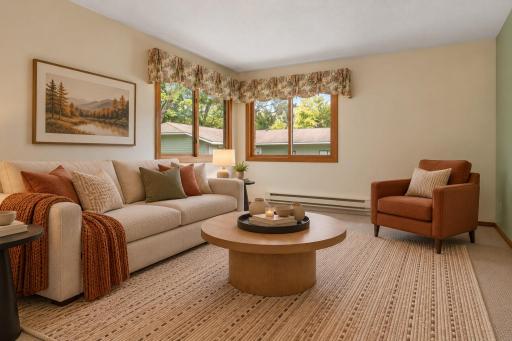Large corner windows create a bright, airy feel in the living room, with treetop views adding a sense of privacy. A comfortable setting to relax and enjoy the seasons from indoors. (Virtually staged photo.)