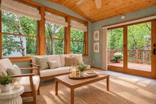 A standout four-season porch surrounded by windows offers beautiful views of mature trees, with a warm wood ceiling and direct access to the deckâan inviting retreat in every season. (Virtually staged photo.)