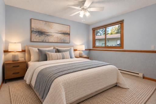 One of two lower-level bedrooms, conveniently located near the full bath featuring a jetted tub and ceramic tile. A laundry closet completes this functional lower-level layout. (Virtually staged photo.)