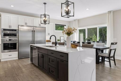 Commercial sized, stainless steel refrigerator and freezer. Five burner gas cooktop. Double ovens