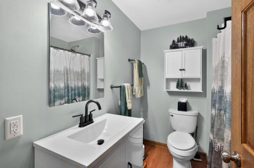 Updated 3/4 bath features a new shower, vanity, lighting, toilet and shelving completed in 2025.