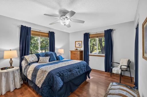 Primary bedroom featuring hardwood floors, dual windows, and a ceiling fan for added comfort.