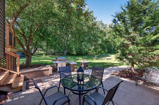 Large patio creates an inviting outdoor gathering area surrounded by mature trees.
