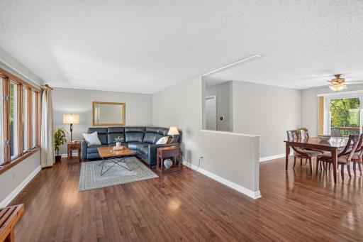 Open-concept living and dining spaces feature newer hardwood floors and a wall of windows