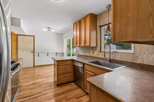 Kitchen with wood cabinetry, stainless steel appliances, and an adjoining casual dining area.