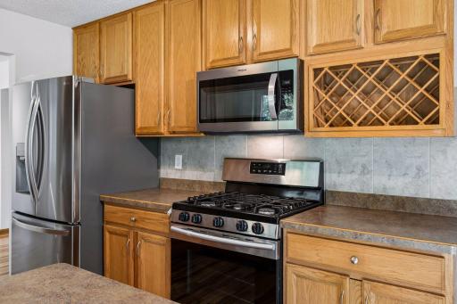 Gas range, stainless steel refrigerator and microwave, and built-in wine storage.