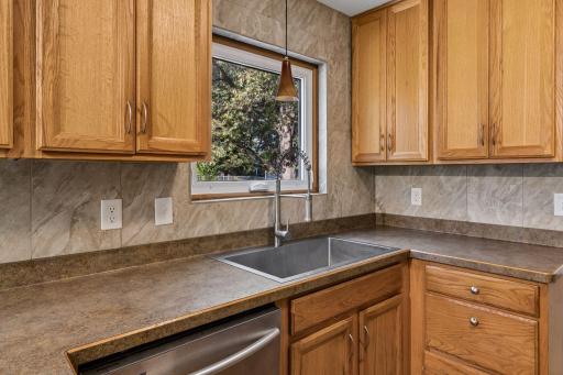 Kitchen sink beneath a backyard-facing window, with surrounding counter and cabinet space.