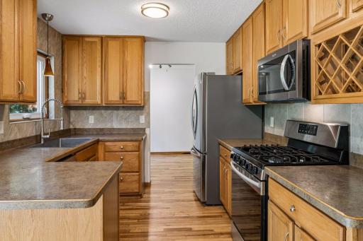 Kitchen with hardwood flooring, wood cabinetry, and stainless steel appliances.