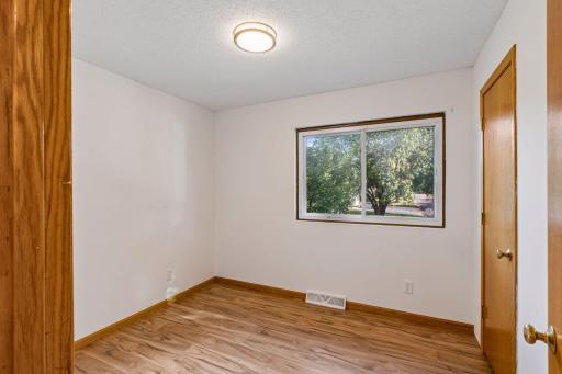 Upstairs bedroom two with hardwood flooring and a front-facing window.