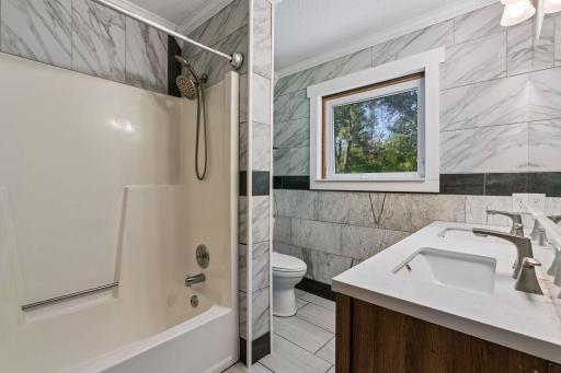 Full bathroom with a tub/shower combination, tile finishes, and a double-sink vanity.