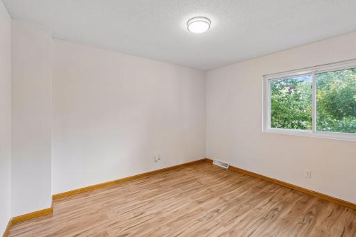 Upstairs bedroom three with hardwood flooring and views of mature trees.
