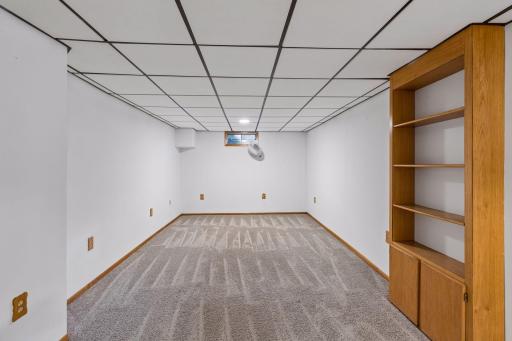 Lower-level recreation room with built-in shelving and cabinet storage.