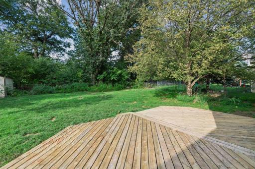 Spacious backyard deck overlooks the lawn and mature trees.