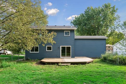 Rear exterior with blue siding, white trim, and a broad backyard deck.