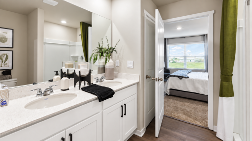 A private retreat complete with dual vanities, a generous shower, linen storage, and direct access to the walk-in closet. *Photo of similar home. Virtually staged.