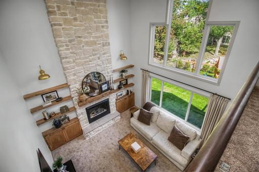 Upper-level view showcases the dramatic two-story living room and fireplace below.