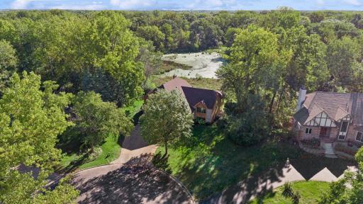 Aerial view highlights the private cul-de-sac location, mature trees, spacious lot, and pond directly behind the home.