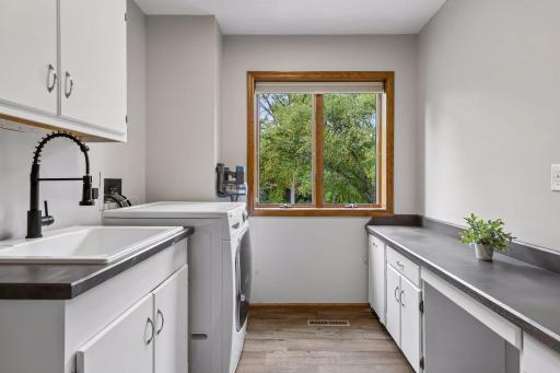 Convenient upper-level laundry with utility sink, generous cabinetry, and counter space - right where you need it near the bedrooms.