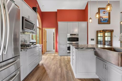 Another kitchen view showcases the double oven, gas cooktop, extensive cabinet storage, stainless steel appliances, and oversized center island with additional storage.