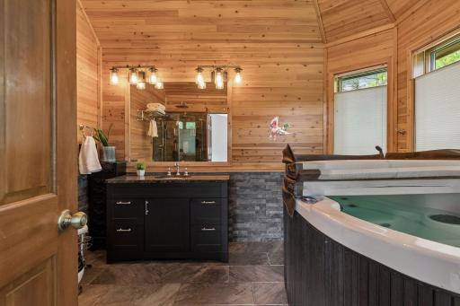 Spa-inspired primary bath with warm wood finishes, hot tub, large vanity and a relaxing retreat feel right at home.