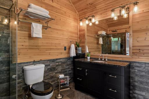 Beautifully finished primary bath with large vanity, stone accents, and warm wood walls for a distinctive spa-like atmosphere.