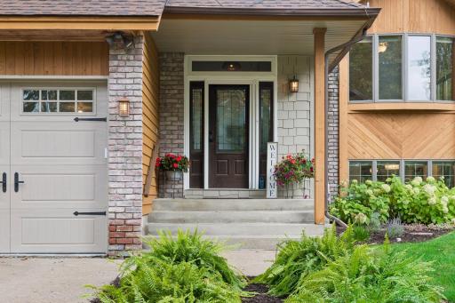 Inviting covered front entrance with double doors, sidelights, and mature landscaping.