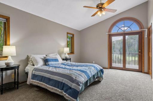 Spacious primary suite with vaulted ceiling, abundant natural light, and private deck access overlooking the pond and surrounding nature.