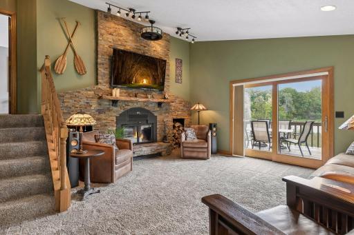 Spacious main-level living room with vaulted ceiling, wood-burning stone fireplace and walkout to the deck overlooking the pond.