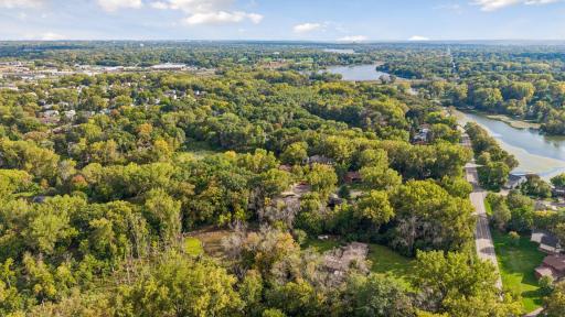 Aerial view showcases the home’s beautiful wooded setting near Gervais Lake, surrounded by mature trees, water, and established neighborhoods.