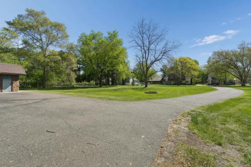 Backyard view featuring the asphalt driveway leading to the additional detached building