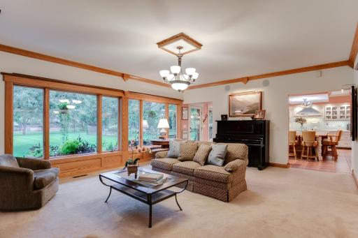 Living room featuring a cozy gas fireplace, 9-foot ceilings, stunning 11-inch smooth cedar trim, Andersen Perma-Shield windows, and convenient access to the kitchen.