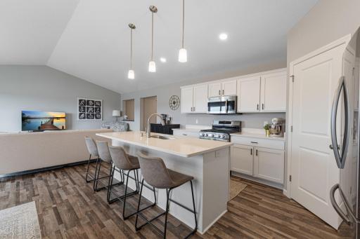Open kitchen with LVP flooring, quartz countertops and stainless steel appliances.