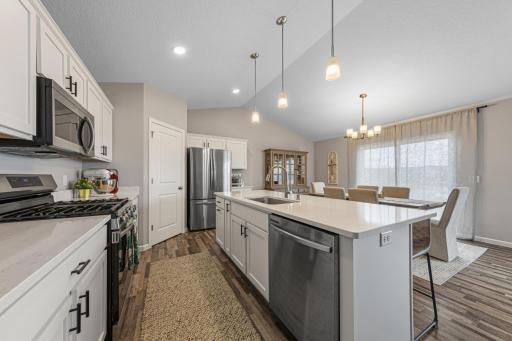 Another view of open kitchen and dining area with LVP flooring, quartz countertops and stainless steel appliances.