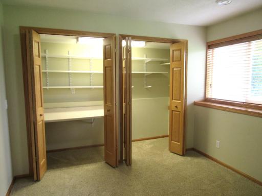 Extra deep lighted closet in the lower level bedroom with shelving and a crafting table.