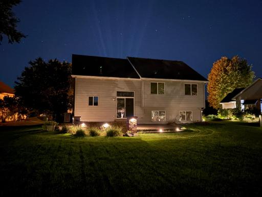Rear view of the home with upscale lighting around the patio.