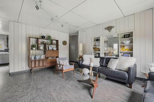 The living room is bright and open, with original wall panels and generous natural light.