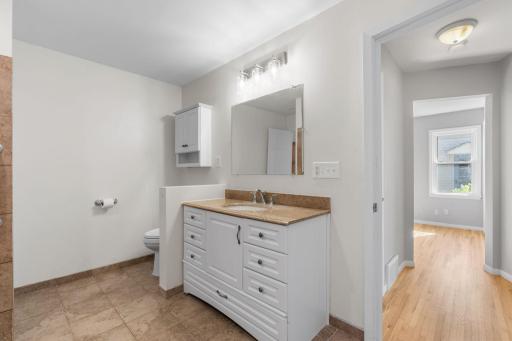 Bright full bath complete with clean white vanity, updated lighting, and built-in storage.