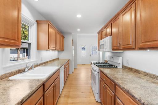 Functional kitchen with ample solid wood cabinetry, gas range, generous counter space, and updated fixtures.