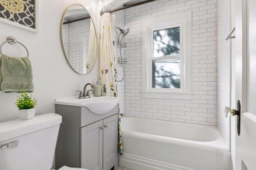 Updated full bathroom featuring a tiled tub/shower surround, modern vanity and natural light.