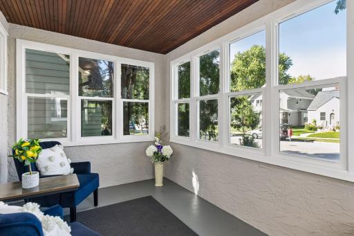 Bright three-season front porch surrounded by windows - an inviting bonus space for morning coffee, reading, or relaxing.