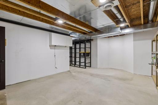 This large storage room offers abundant space for seasonal items and household supplies, with metal-framed wood shelving and a storage-bin organization system already in place. The versatile space could also accommodate a home gym or workshop.