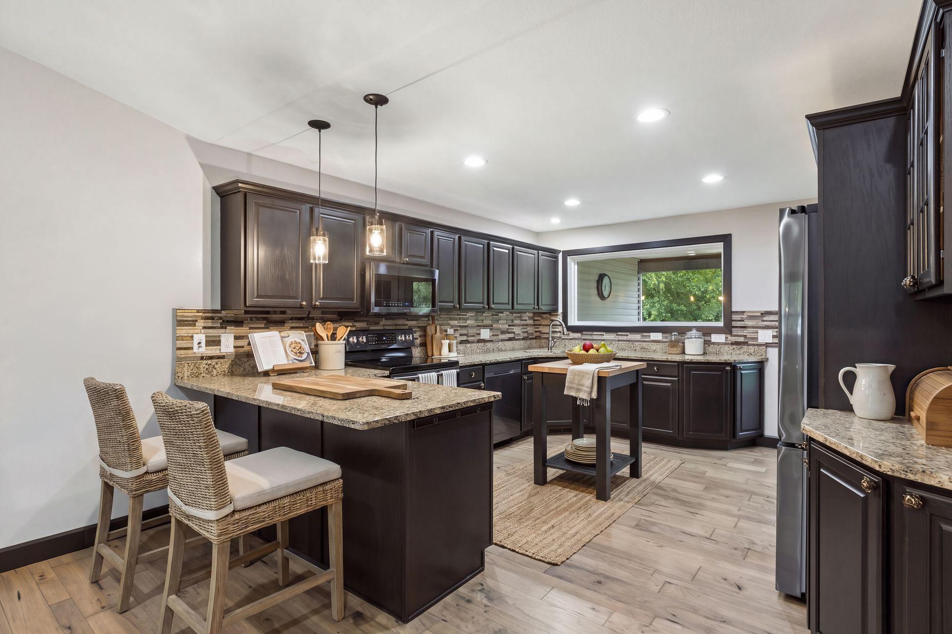 The spacious kitchen offers rich espresso-finished cabinetry, granite countertops, a tile backsplash, and generous workspace for cooking and entertaining. The breakfast bar perfectly complements this amazing kitchen.