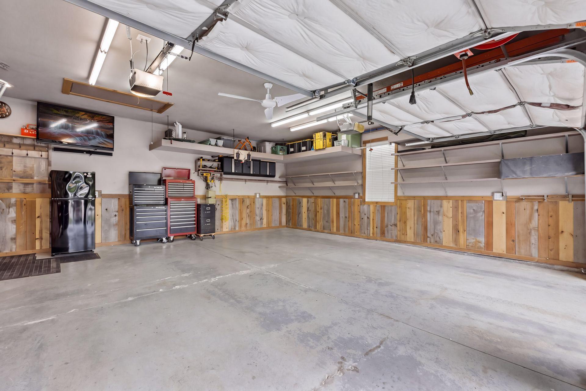 Custom shelving, tool organizers, and a pull-down attic ladder provide excellent storage. The reclaimed-wood wainscoting and built-in air-compressor line make this garage a fully customized and functional workspace.