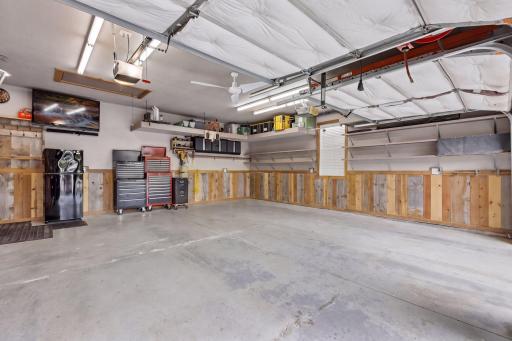 Custom shelving, tool organizers, and a pull-down attic ladder provide excellent storage. The reclaimed-wood wainscoting and built-in air-compressor line make this garage a fully customized and functional workspace.