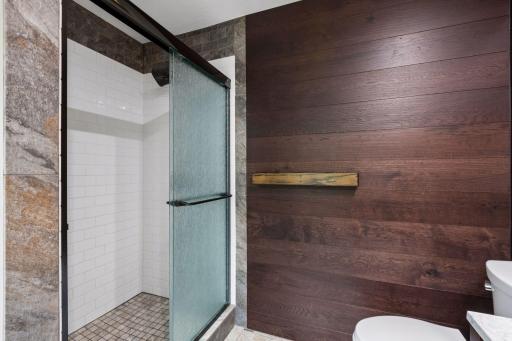 Custom tilework, a rain-glass shower door, and an oversized showerhead complete the thoughtfully remodeled primary bathroom.