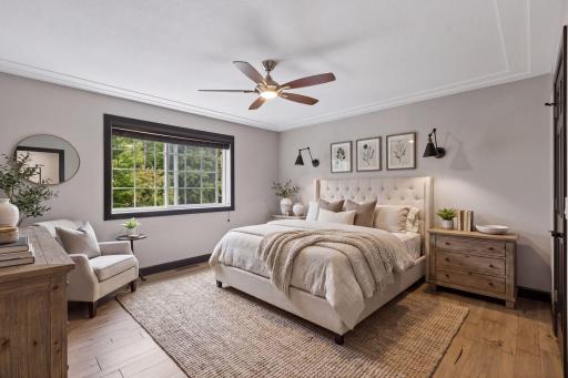The acacia wood flooring continues into the main-level primary bedroom, featuring a tray ceiling, updated lighting, and peaceful views of the wooded setting. Enjoy the convenience of a private ensuite and spacious walk-in closet with a built-in safe.