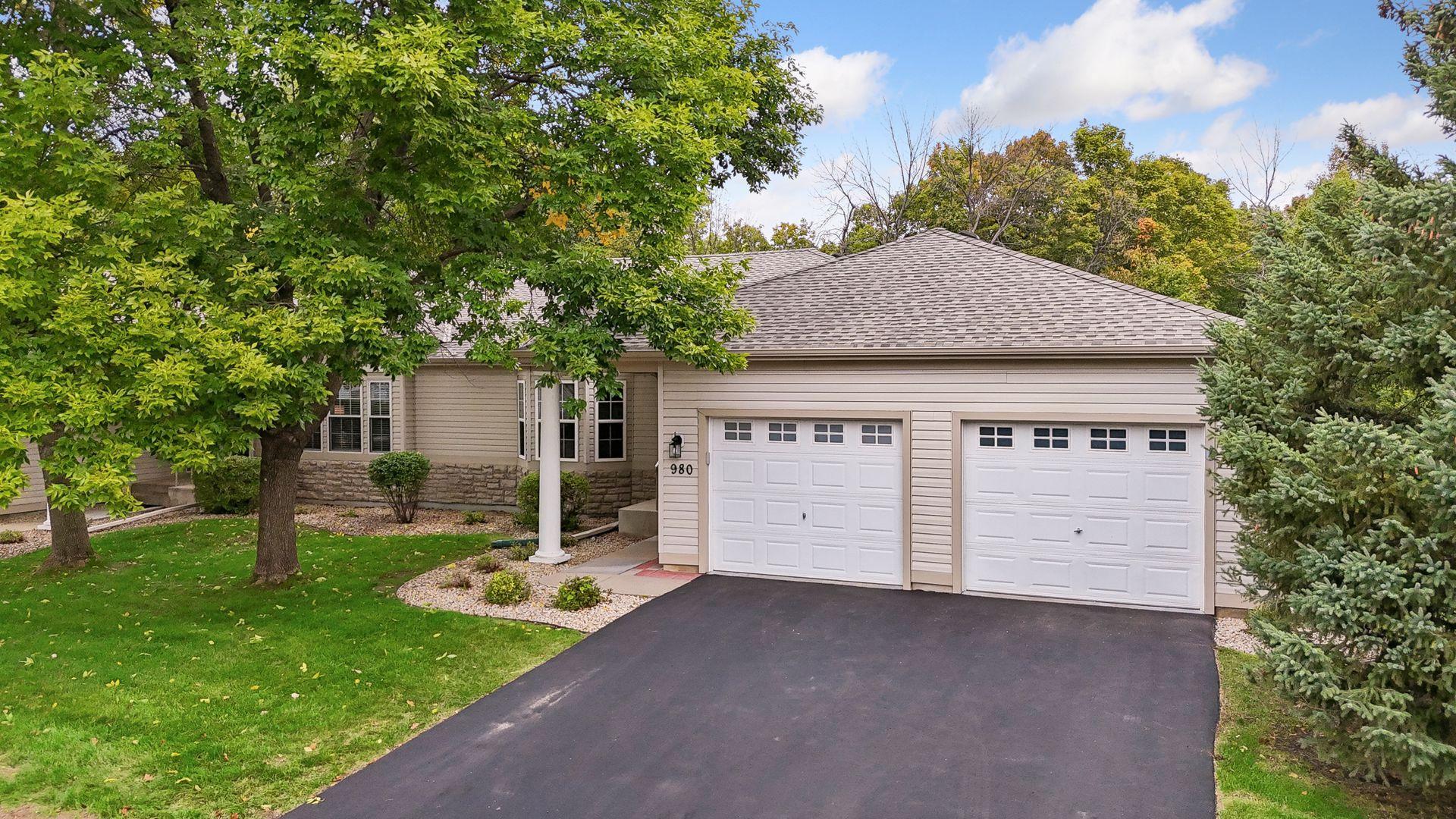 The mature trees and well-maintained lawn frame the welcoming front entrance of this thoughtfully customized one-level townhome.