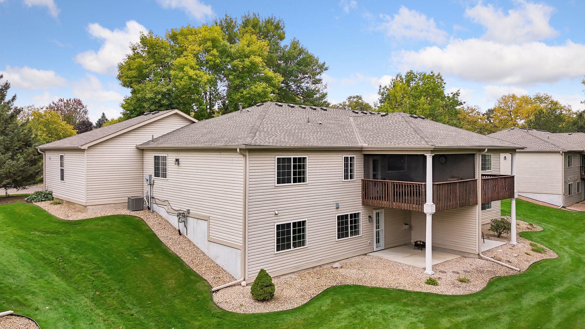 The walkout design provides two covered outdoor living spaces: an upper-level deck with removable screens and a lower-level patio overlooking the peaceful green space.