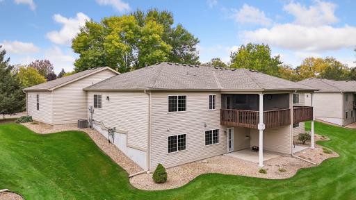 The walkout design provides two covered outdoor living spaces: an upper-level deck with removable screens and a lower-level patio overlooking the peaceful green space.
