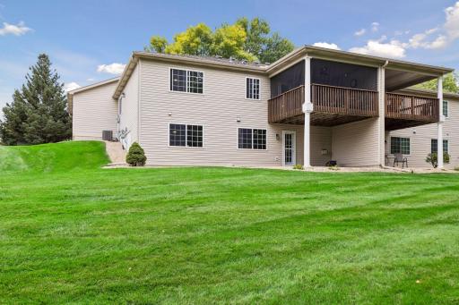 The rear view highlights the homeâs walkout lower level, covered patio, screened deck, and expansive shared green space.